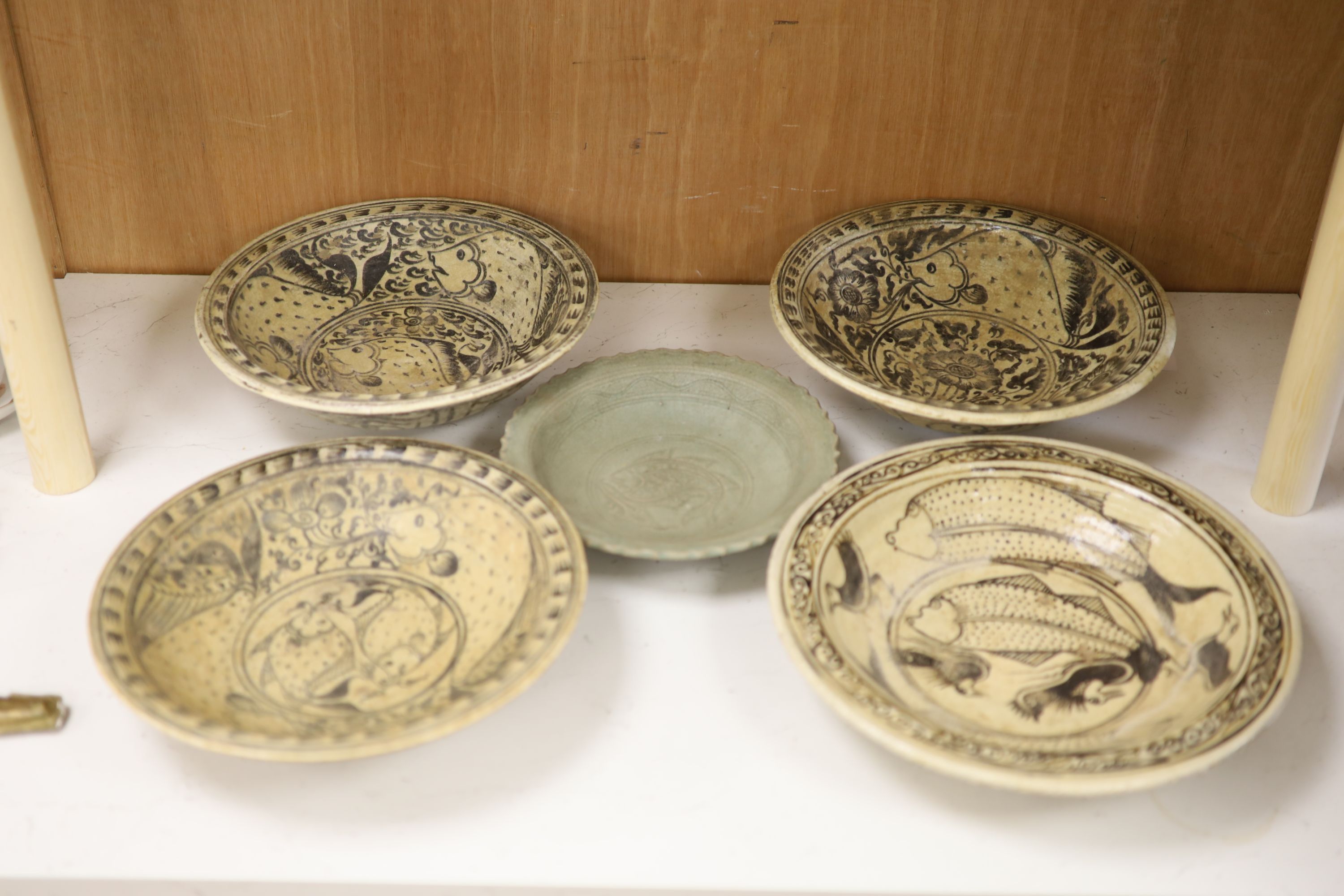 Four Sukhothai style dishes and a Thai celadon dish, diameter 32cm